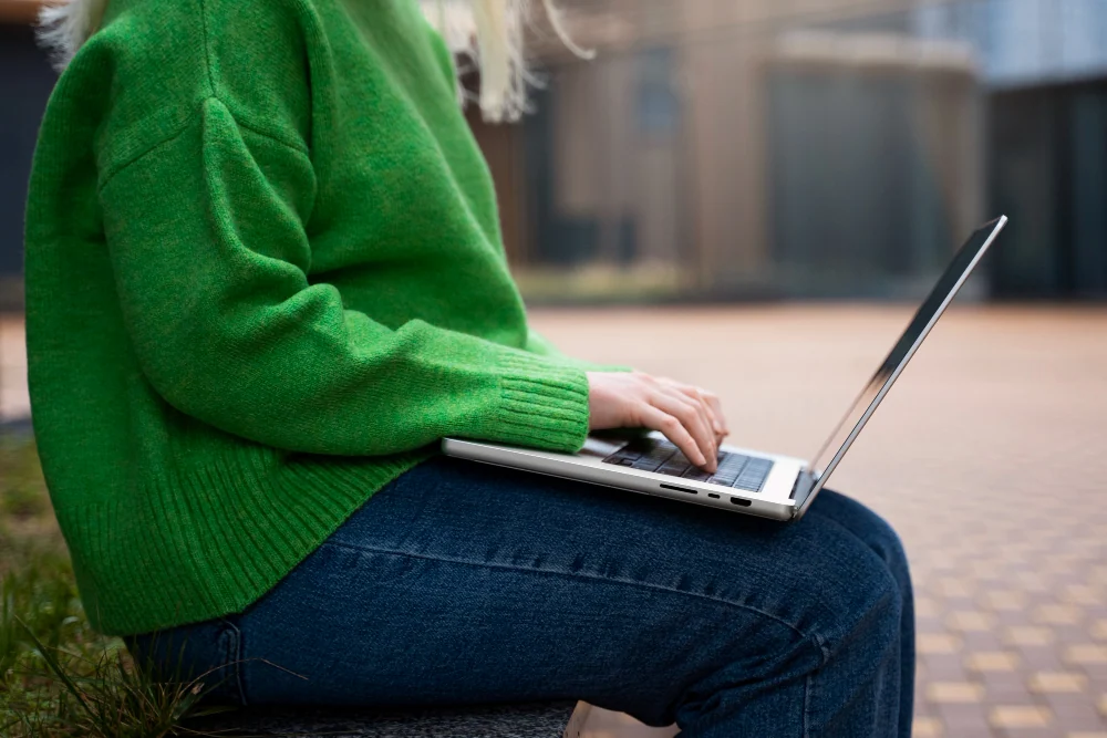 Femme avec un pull vert travaillant sur un ordinateur portable